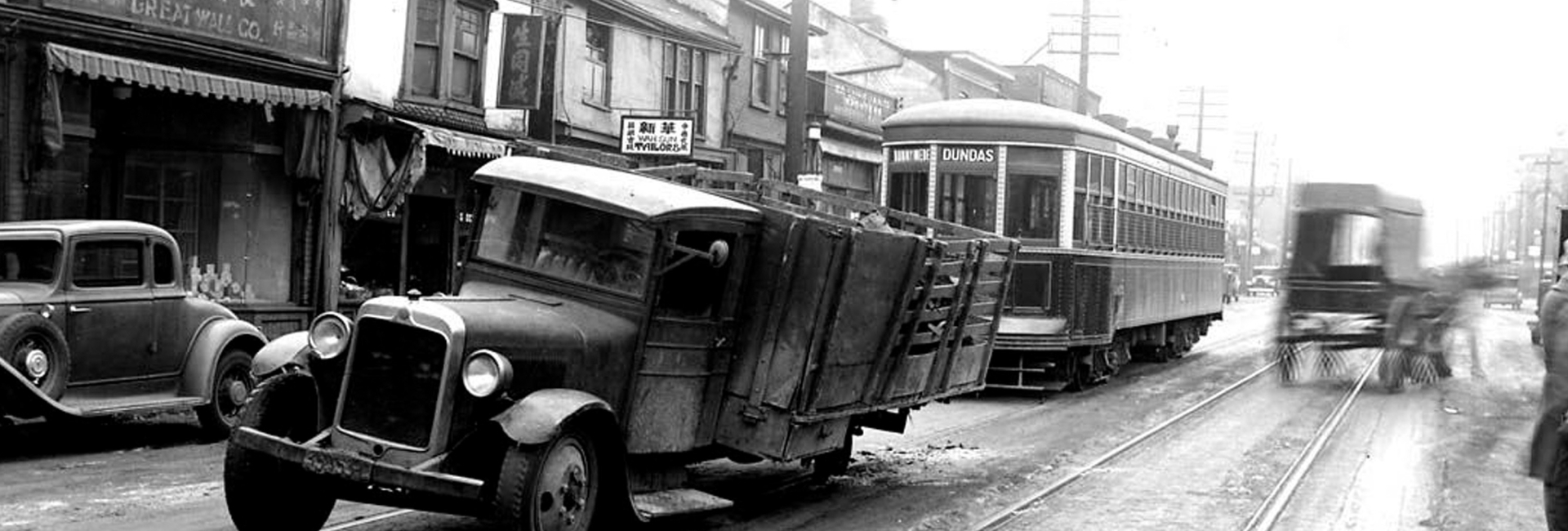 Vintage street scene with a truck stalled on streetcar tracks as a Dundas streetcar approaches.