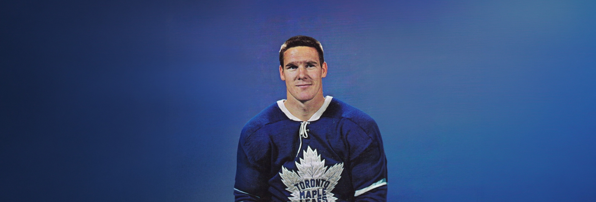 Portrait of a hockey player wearing a Toronto Maple Leafs jersey against a blue background.