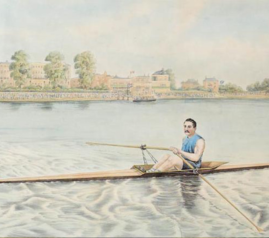 A lone rower in a blue sleeveless shirt navigates a narrow wooden sculling boat across calm water, leaving gentle ripples behind. A row of large trees and historic-looking buildings line the far riverbank beneath a bright, lightly clouded sky.