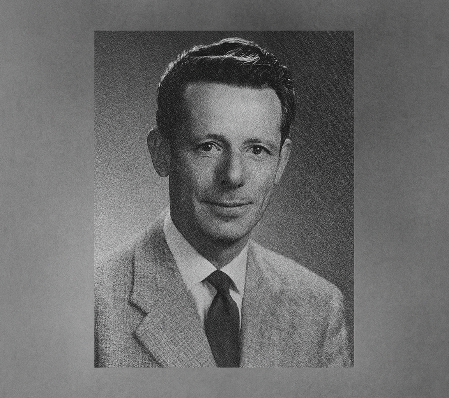 A black and white photos of Gus Harris during his time as a reeve in Scarborough. He is wearing a plaid suit jacket, white-coloured shirt, and dark-coloured tie. His hair is cropped short and slightly wavy and his expression is neutral but pleasant.