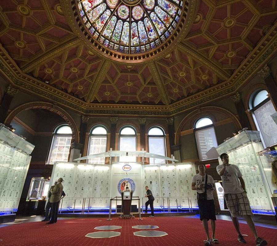 The Esso Great Hall is a vast 70‑by‑70‑foot space crowned by a 45‑foot stained‑glass dome—the largest of its kind in Toronto. The dome’s 24 panels show symbolic dragons and eagles, surrounded by fruit and floral motifs, with central emblems representing Canada and its original provinces.