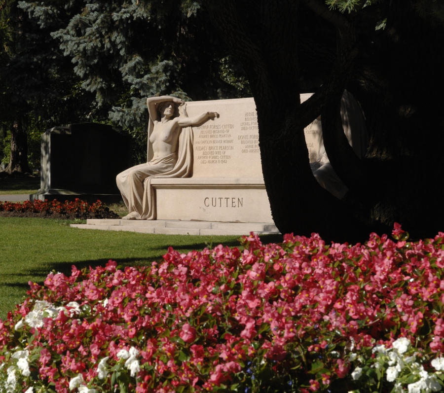 large granite bench with naked granite woman and trees and flowers