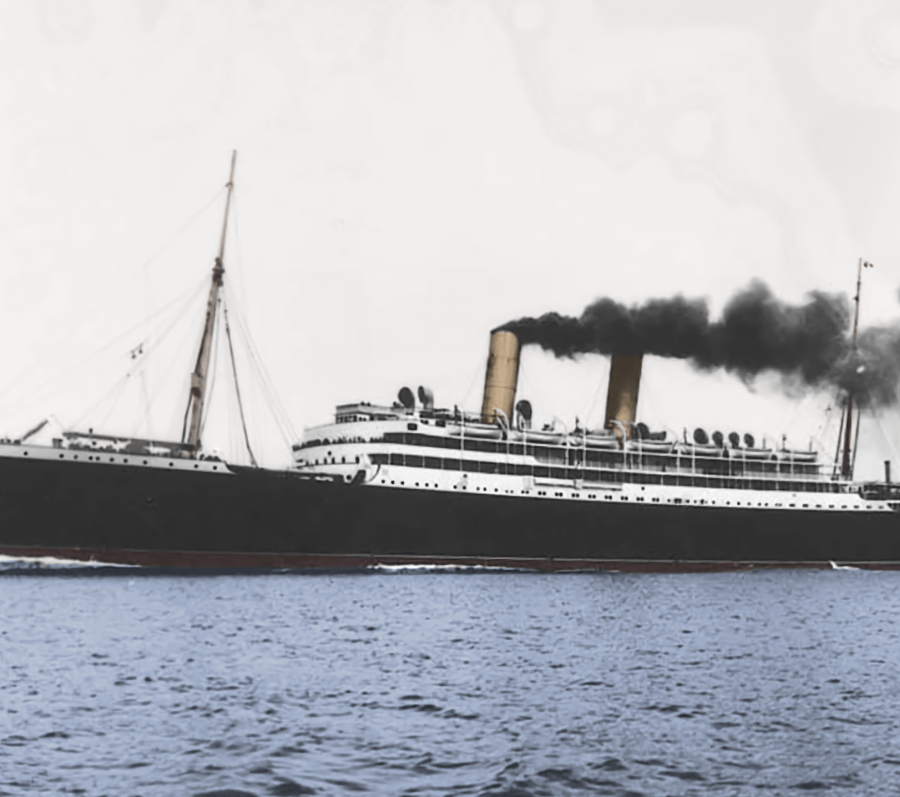 A large early‑20th‑century ocean liner with a black hull and white superstructure steams across calm water, emitting dark smoke from multiple funnels, viewed broadside against a pale sky and distant shoreline.