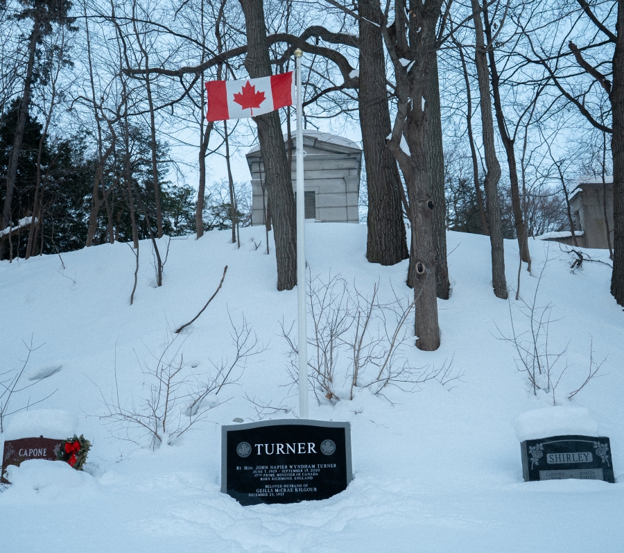 grave covered in snow with a Canadian flag