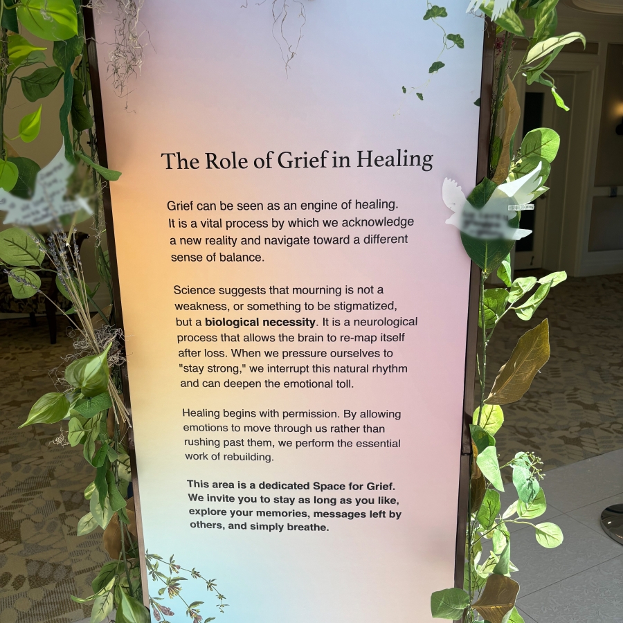 Sign titled “The Role of Grief in Healing” surrounded by greenery