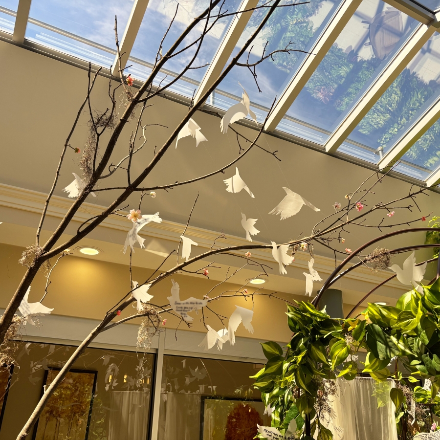 Decorative branches with hanging white bird shapes under skylight