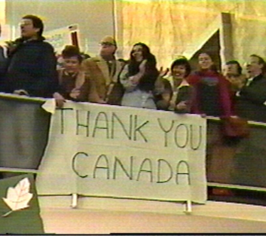 people holding up a big sign that says thank you canada