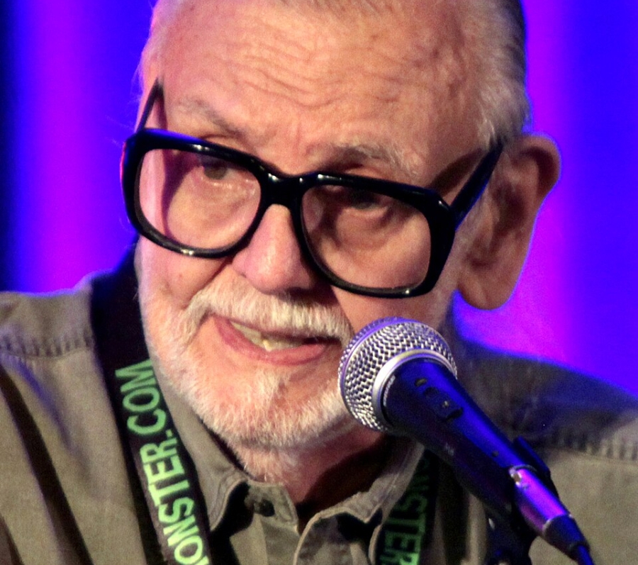 man with glasses speaking at a microphone