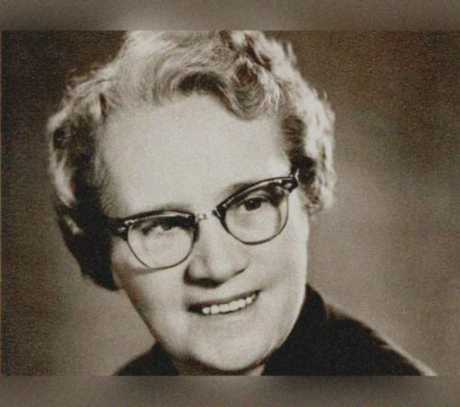 Colour portrait of a person shown from the shoulders up, with light, curly hair against a softly textured, warm‑toned background. The image has a grainy, archival appearance.