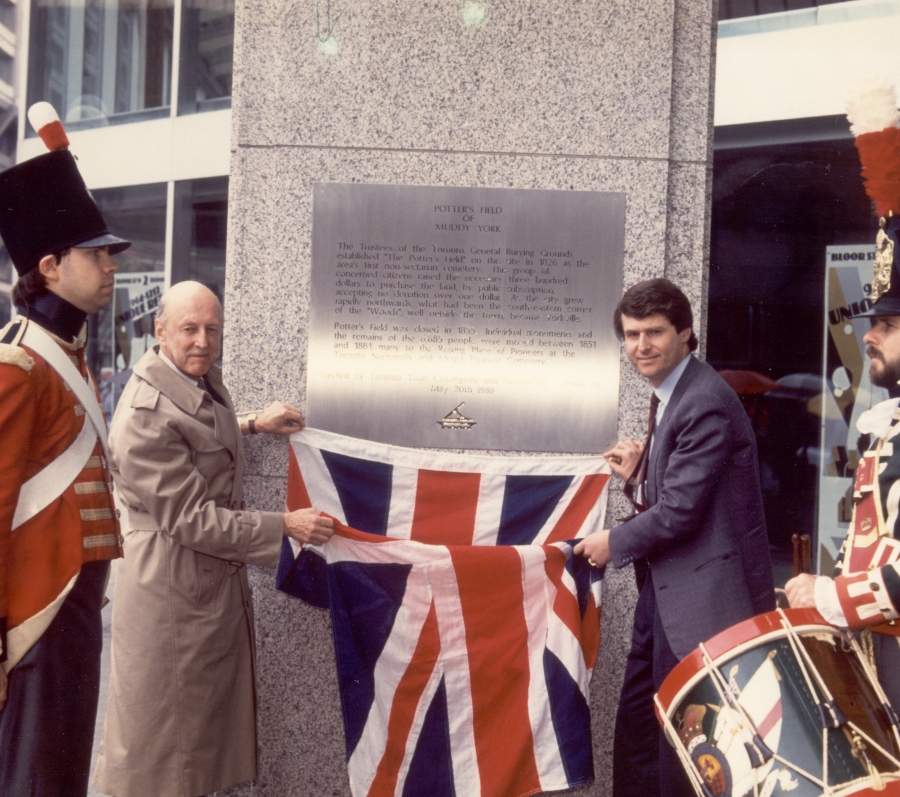 two men unveiling a plaque alongside queen's soldiers