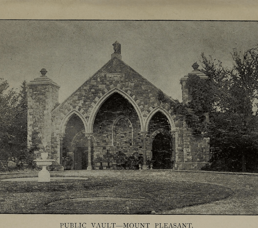 Alt text: Black-and-white historic photograph of a stone Gothic-style building labeled “Public Vault—Mount Pleasant,” featuring three pointed arch entrances and set within a landscaped cemetery.