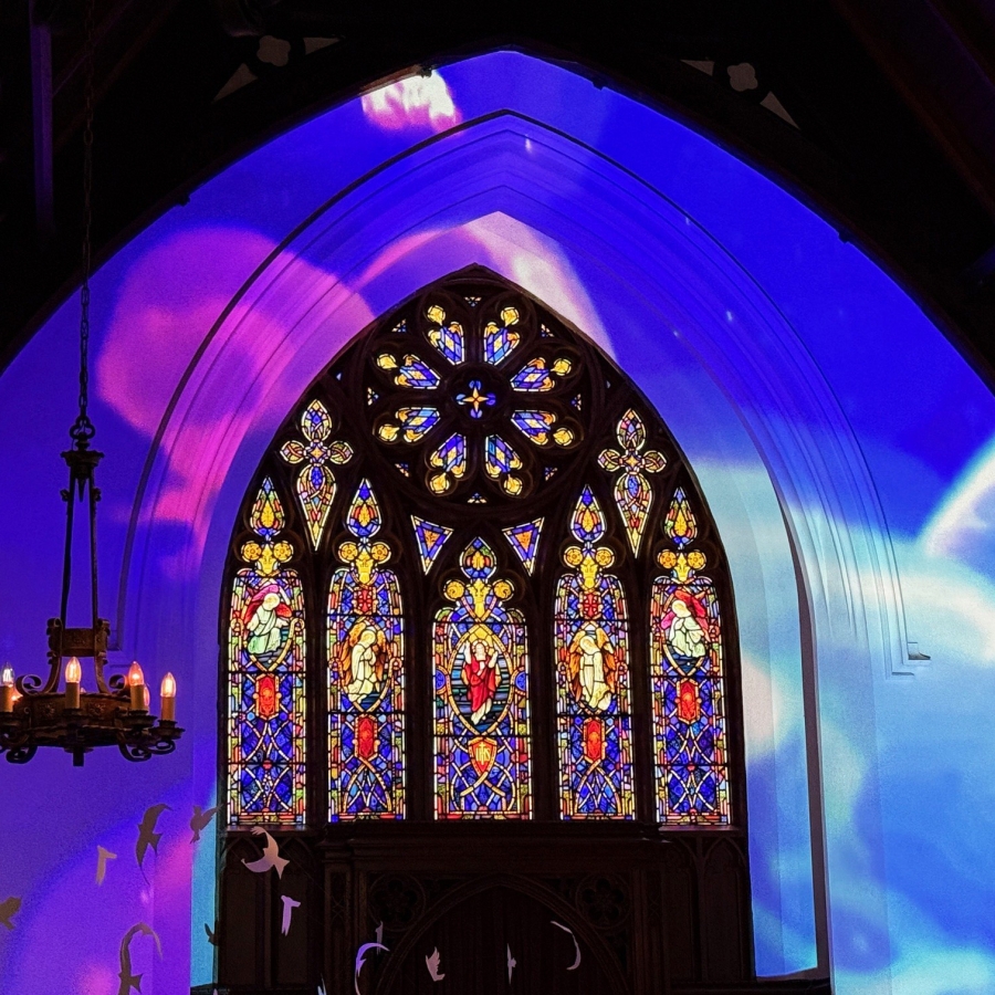 Stained glass window in a church with colorful light across arched ceiling