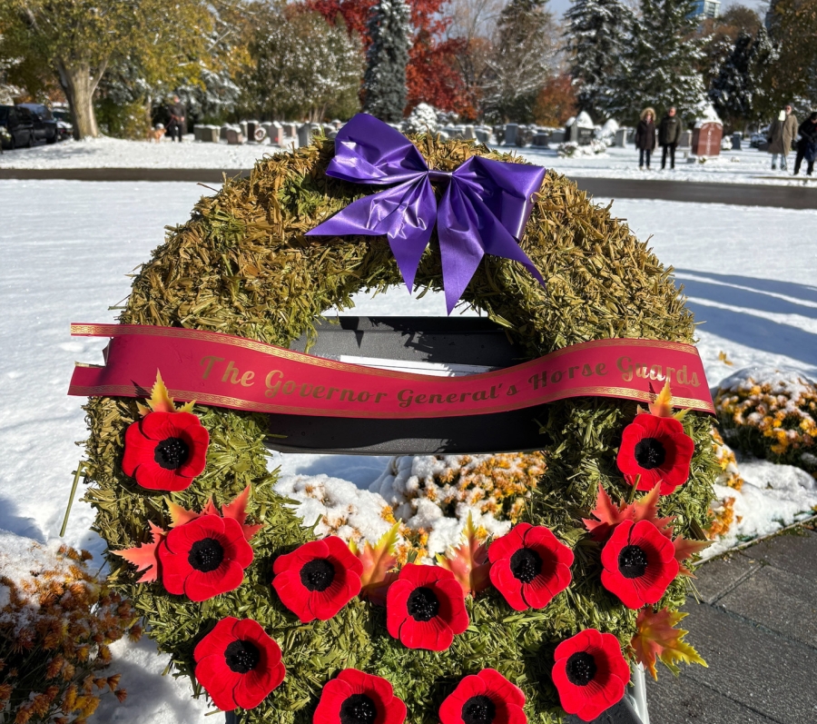 Remembrance Day wreath with red poppies and purple bow displayed at York Cemetery.
