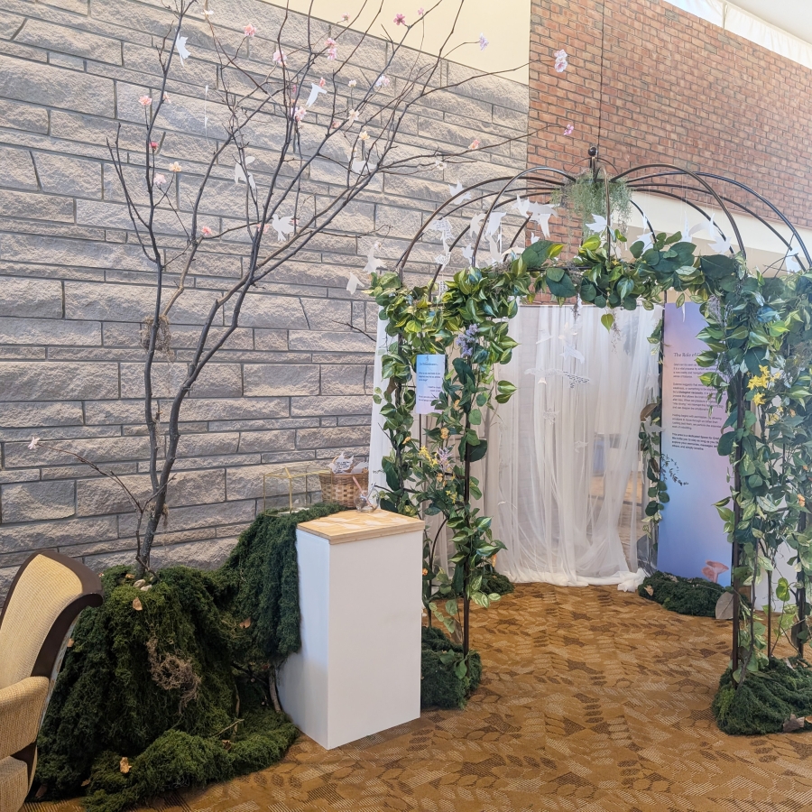 Leafy arch display with hanging white bird cutouts beside a decorative tree