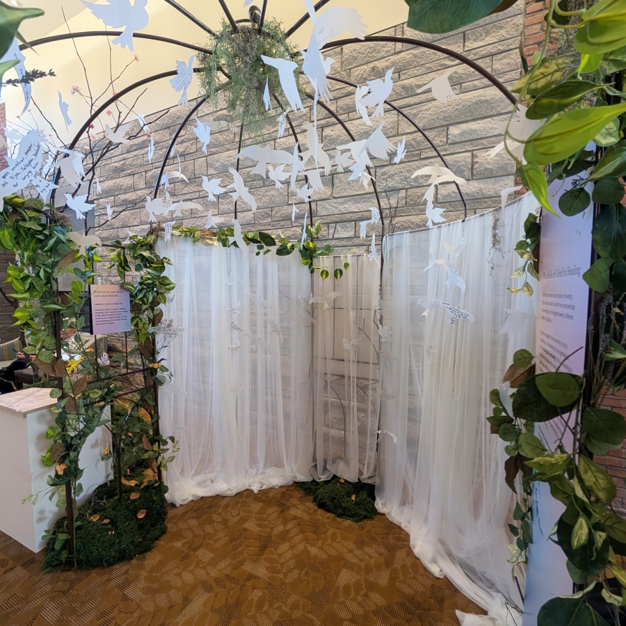 White bird cutouts hanging under a leafy arch with sheer curtains