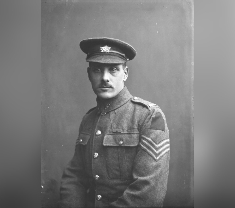 Black-and-white studio portrait of Private Walter Leigh Rayfield, V.C., seated in uniform wearing a service cap and a buttoned military tunic with chevrons on the sleeve, posed against a plain backdrop.