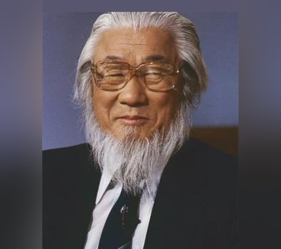Portrait of the Very Rev. Dr. Sang Chul Lee wearing a dark suit jacket, white shirt, and patterned tie, shown from the shoulders up against a plain studio background
