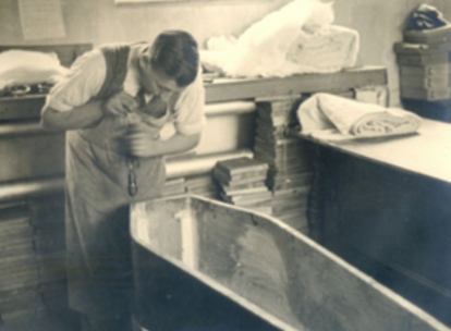 Man carefully working inside a coffin in an early funeral workshop.