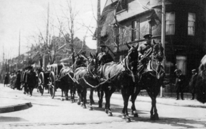 Historic funeral procession with horses and carriages on a city street.