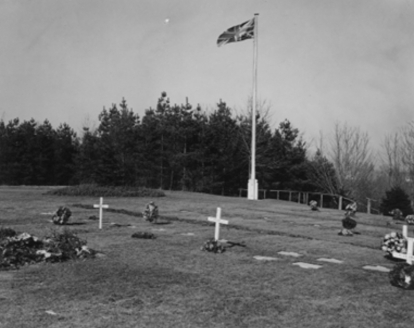 Historic graves marked with white crosses beneath a flagpole.