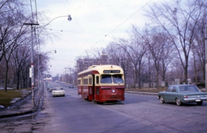 Historic streetcar scene with automobiles on a city street.