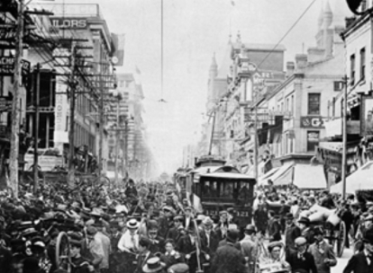 Historic city scene with streetcar and dense pedestrian traffic.