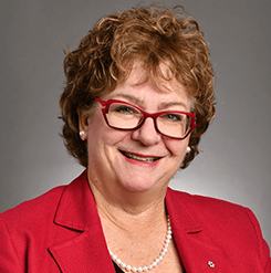 smiling woman with red glasses and red suit jacket