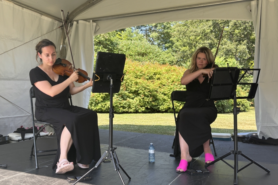 two women playing instruments under a tent