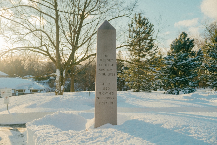 Stone memorial obelisk standing in a snow‑covered park, surrounded by trees in winter. An engraved inscription on the monument commemorates those who lost their lives on 5 July 1970 in Air Canada Flight 621 in Woodbridge, Ontario.