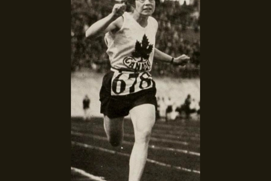A runner wearing a sleeveless jersey with a maple leaf emblem and the word “Canada” sprints on a track, with one leg extended forward and arms pumping. The athlete’s bib number is 678, and a stadium crowd is visible in the background.