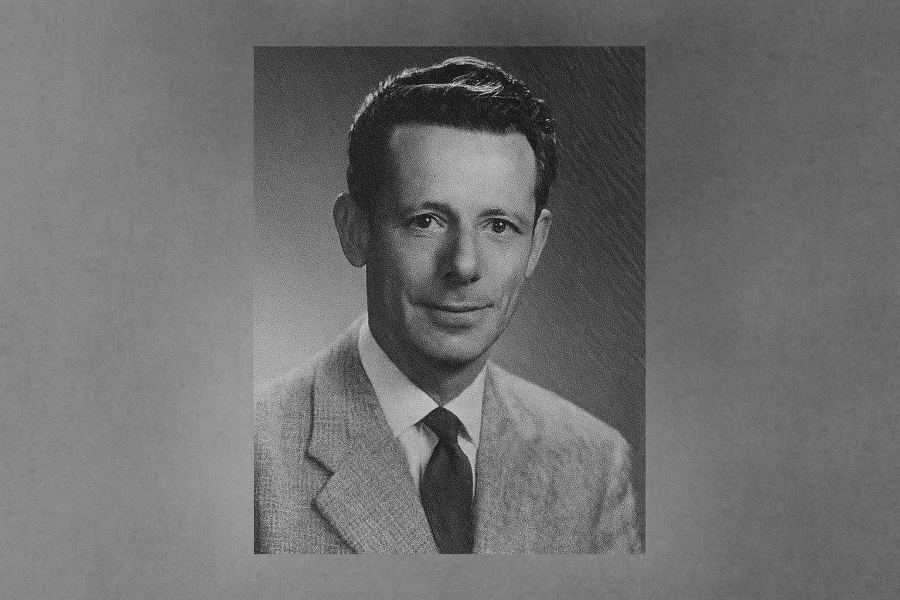 A black and white photos of Gus Harris during his time as a reeve in Scarborough. He is wearing a plaid suit jacket, white-coloured shirt, and dark-coloured tie. His hair is cropped short and slightly wavy and his expression is neutral but pleasant.