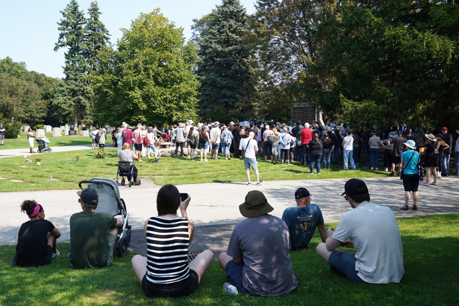 Visitors sitting on the grass watching a guided history tour at Mount Pleasant Cemetery.