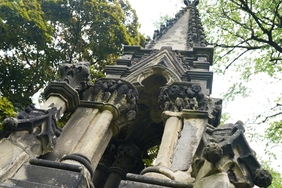 Historic stone mausoleum with ornate columns viewed from below.
