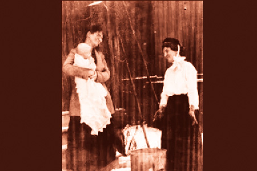 The staged picture entitled “Public health nurse Janet Neilson (right) on a home visit” shows the uniform she had to wear: it includes a black bonnet with white streamers. She carried supplies in a market basket.