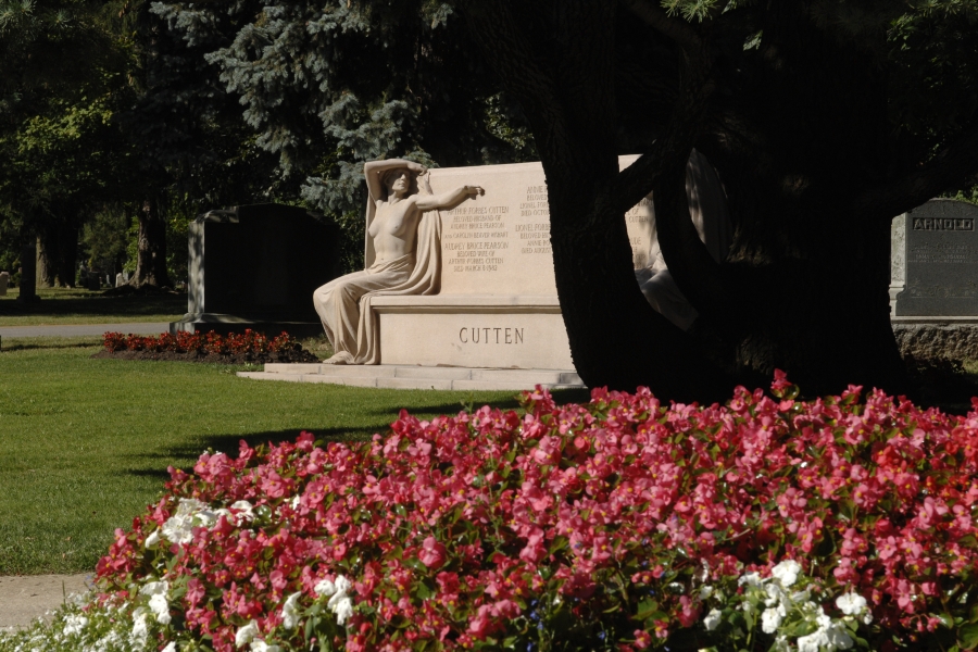 large granite bench with naked granite woman and trees and flowers