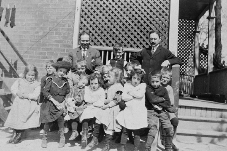 two men in suits standing with a group of young kids