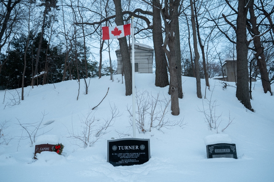 grave covered in snow with a Canadian flag