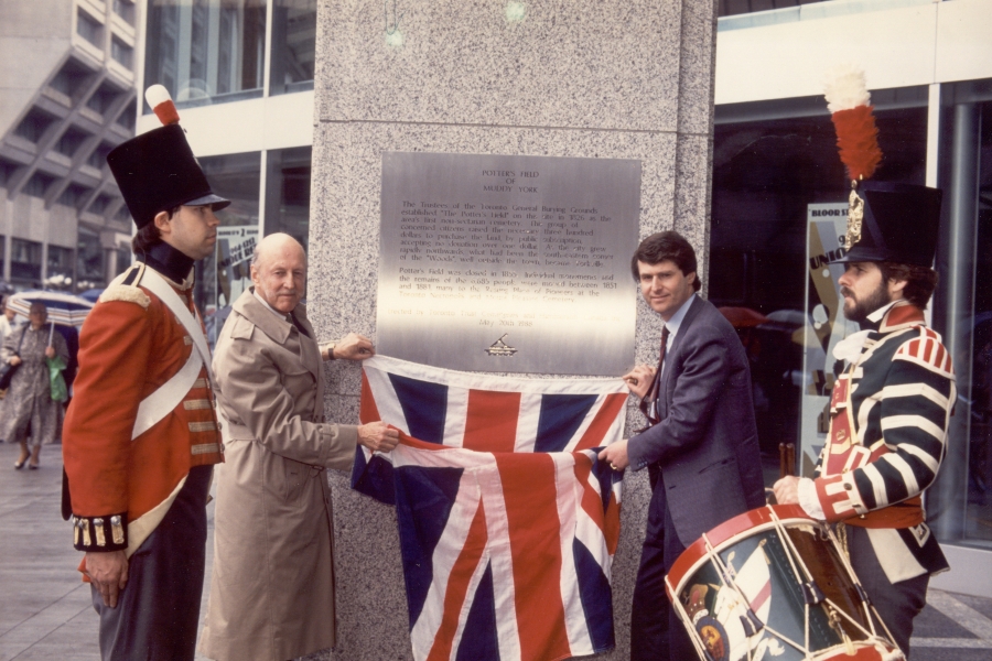 two men unveiling a plaque alongside queen's soldiers
