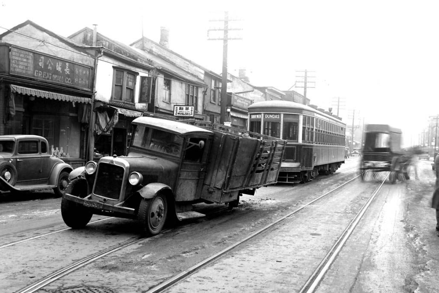 Historic street scene with a stalled truck on streetcar tracks beside a Dundas streetcar.