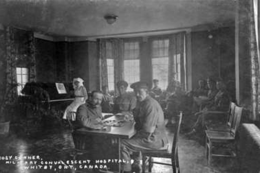 Black‑and‑white photograph of a group of uniformed soldiers gathered on the steps and porch of a large hospital building, some seated and others standing, posed informally in front of tall doors and columns.