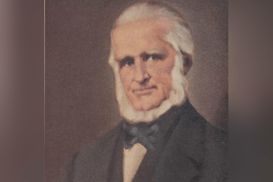Painted portrait of Bartholomew Bull, known as the Patriarch of Spadunk, shown from the chest up wearing a dark suit and bow tie against a muted background.