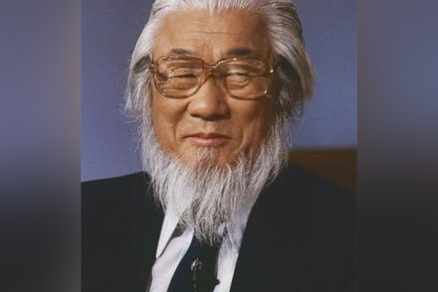 Portrait of the Very Rev. Dr. Sang Chul Lee wearing a dark suit jacket, white shirt, and patterned tie, shown from the shoulders up against a plain studio background