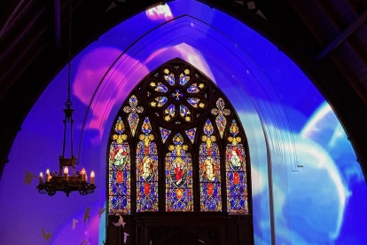 Stained glass window in a church with colorful light across arched ceiling