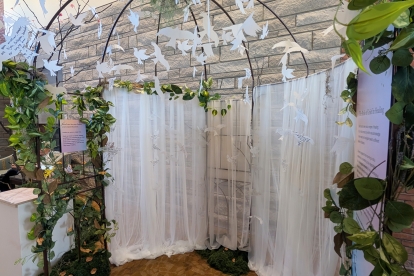 White bird cutouts hanging under a leafy arch with sheer curtains