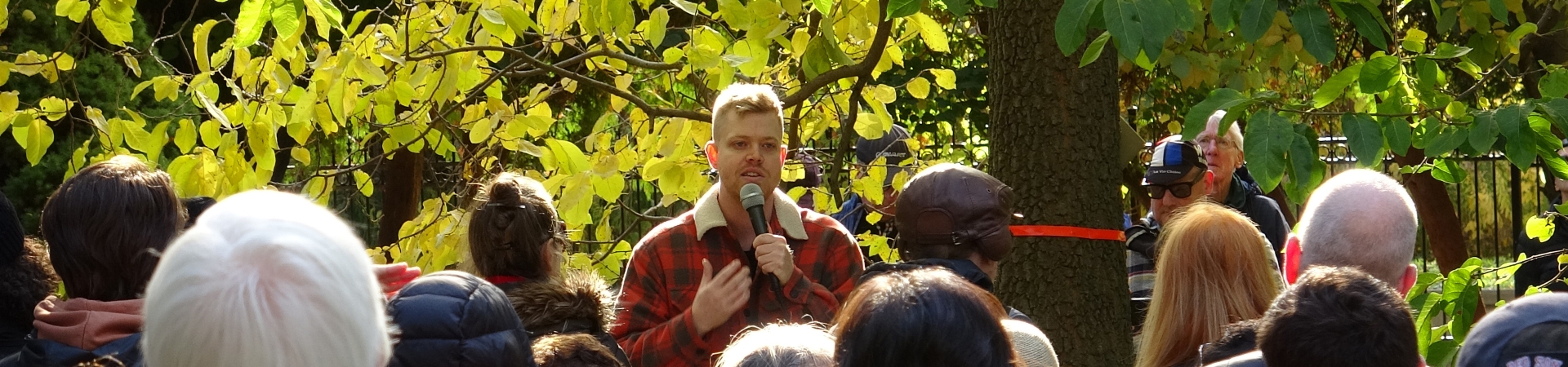 An arborist leading an educational session on urban forestry with people gathered around.